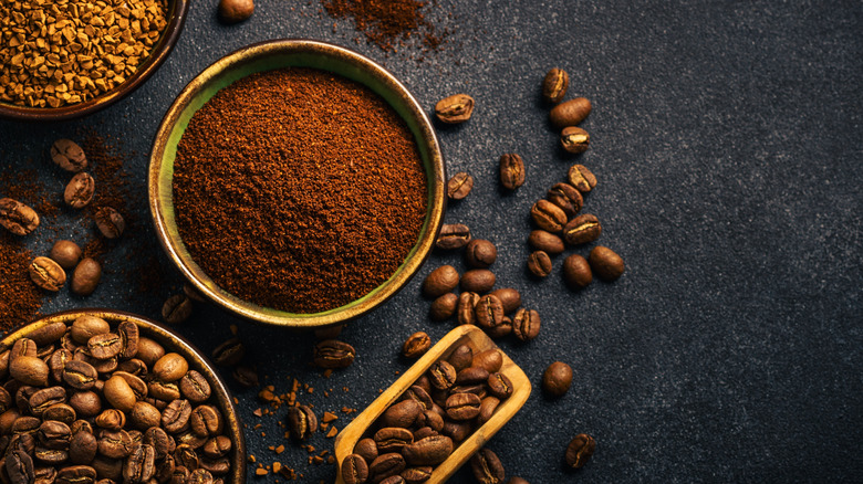 A bowl of coffee beans, ground coffee, and instant coffee on a dark background