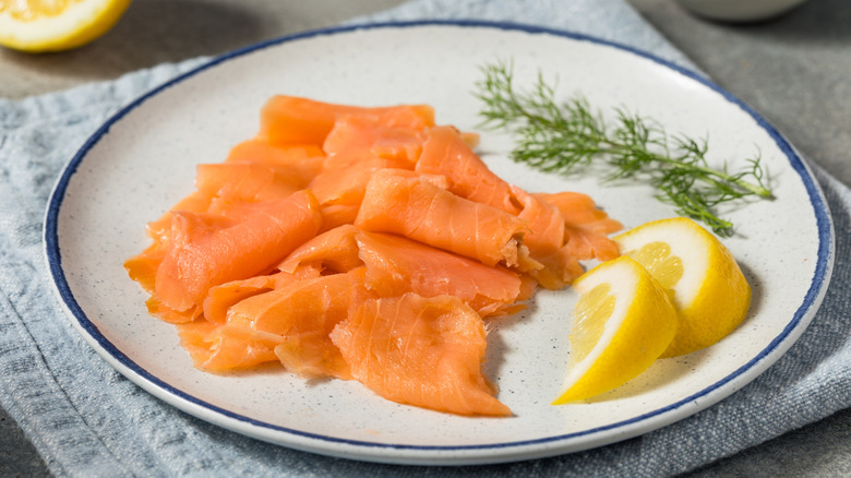 Plate with thinly sliced salmon, dill and lemon slices