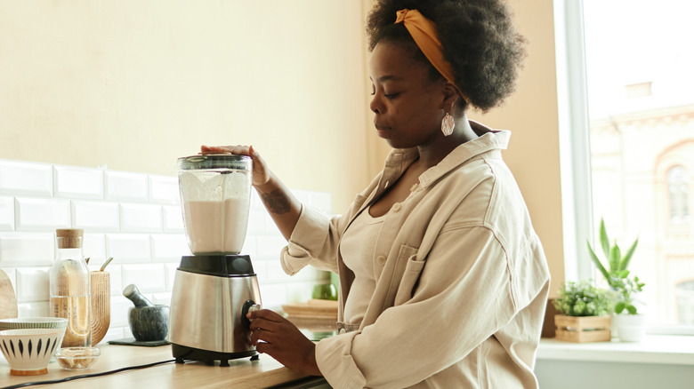 Woman making milkshake in blender