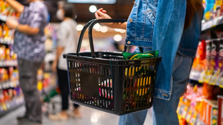 A person holding a shopping basket at the grocery store