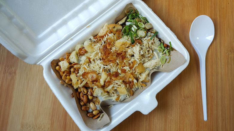 Styrofoam food container with take out on a wooden surface.