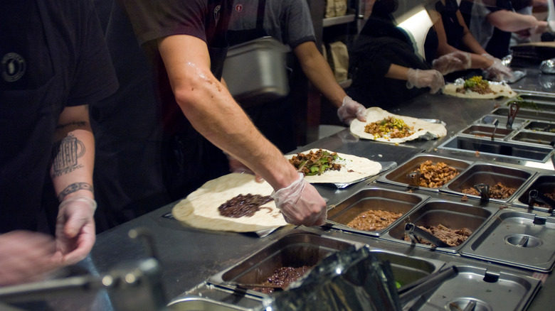 Chipotle workers preparing burritos on the line