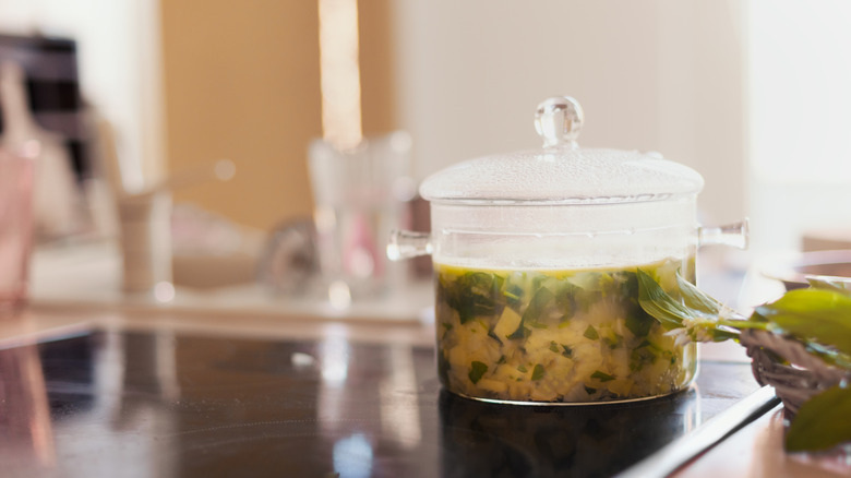 Garlic soup with vegetables cooking in a glass pot on an electric stove