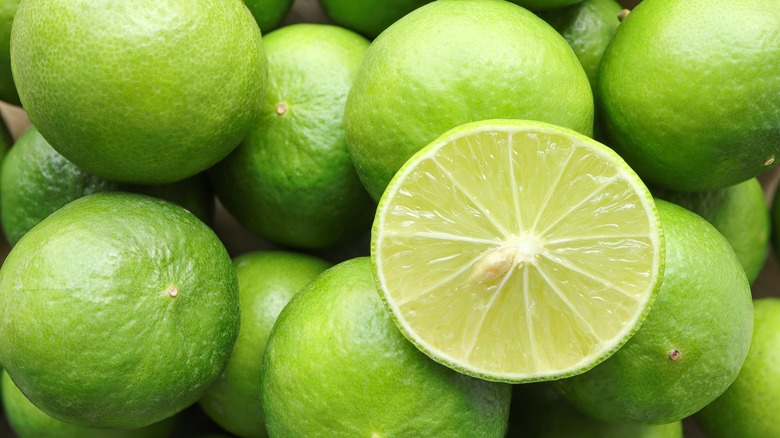 A close up of fresh limes with one cut in half