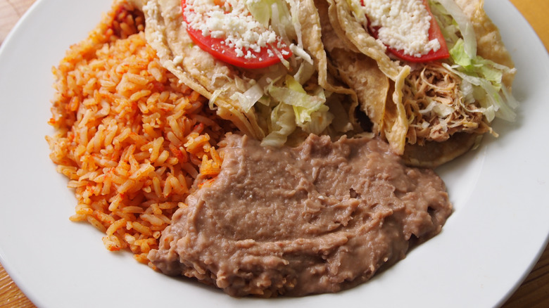 Refried beans on plate with rice and tacos