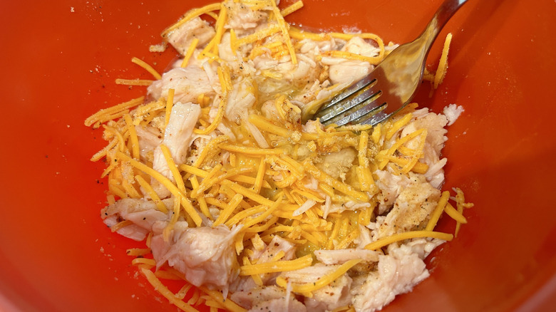 canned chicken with shredded cheddar and an egg in a bowl