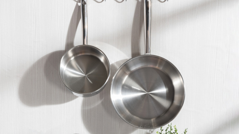 A stainless steel pot and pan hanging from a pot rack in the kitchen