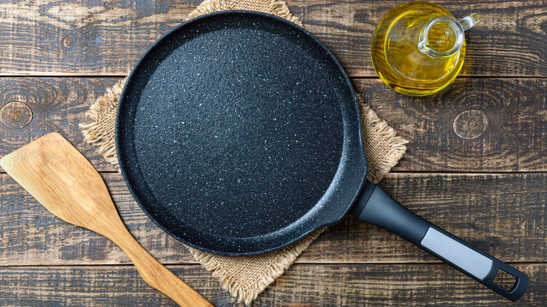 Bird's eye view on a skillet next to a cooking utensil and oil