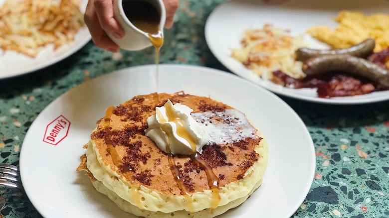 Pouring syrup on pancakes at Denny's