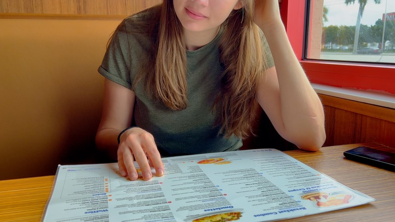 Woman reading IHOP menu