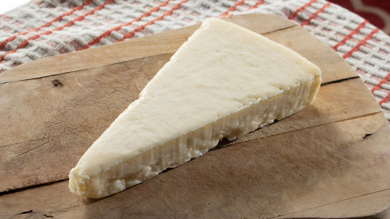 A block of cotija cheese on a cutting board.