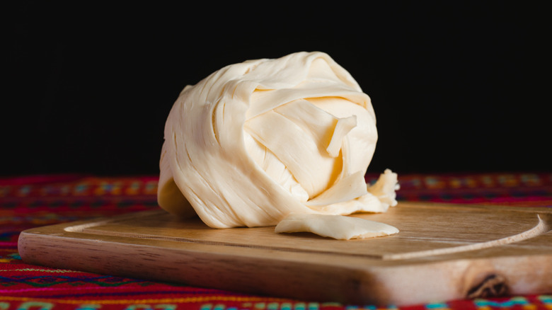 a ball of Oaxaca cheese on a cutting board.