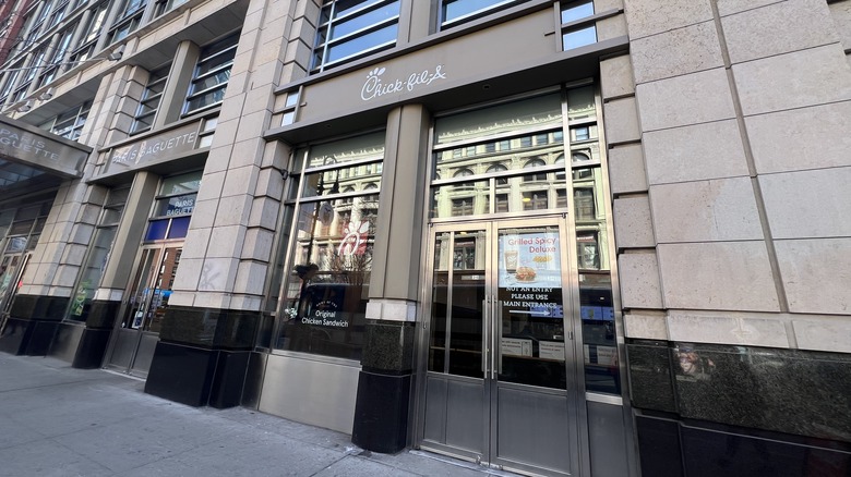 An exterior of a Chick-fil-A restaurant on the ground floor of a taller building is shown in Manhattan.