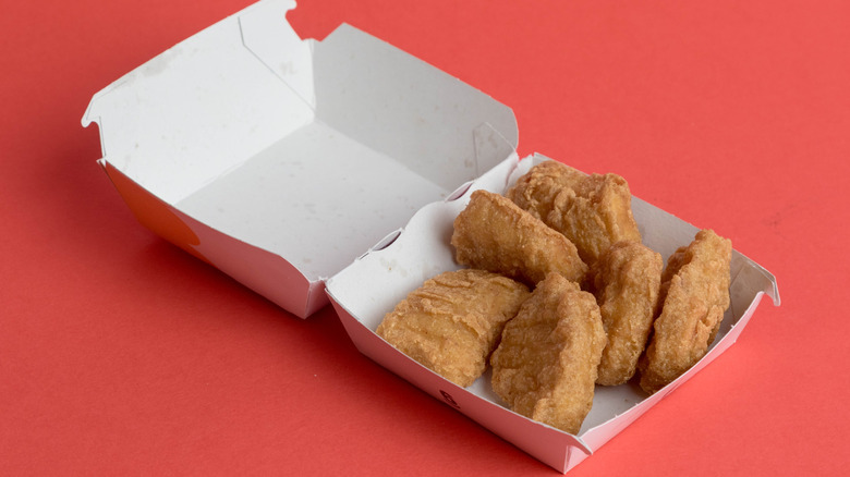 an open box of chicken mcnuggets against a red background