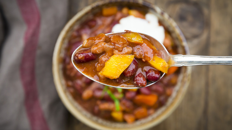 A close up shot of a spoon full of chili