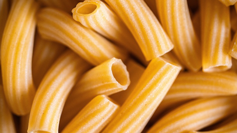 A close up photo of dried rigatoni noodles piled on top of one another.