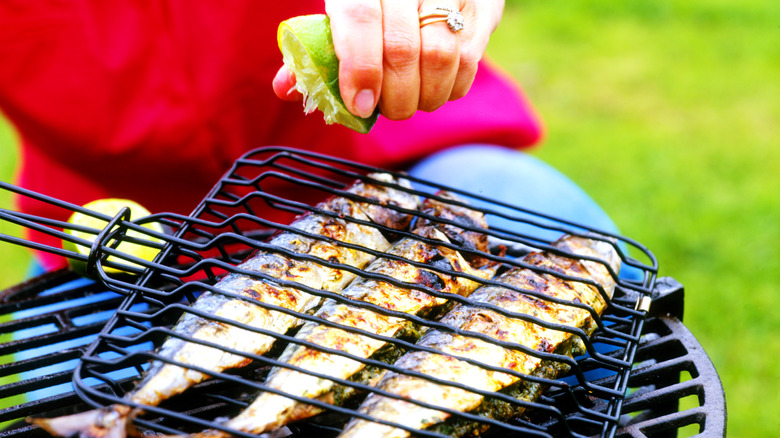 A person squeezing lime onto grilled fish