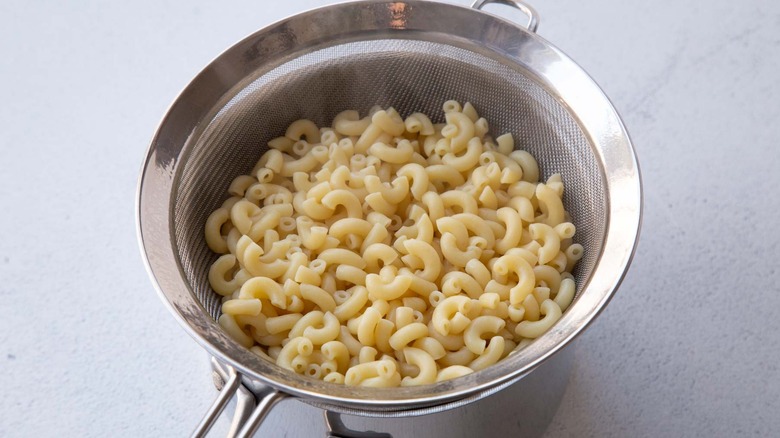 Cooked elbow noodles in mesh sieve