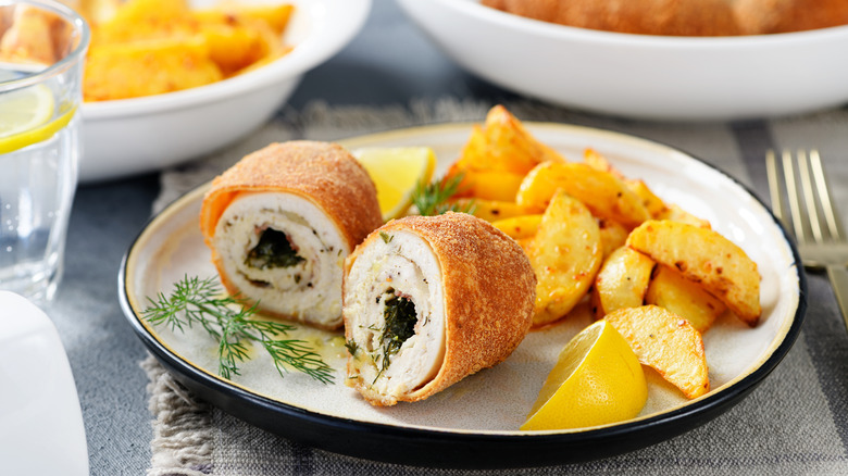 Chicken Kiev on plate with potatoes and lemon