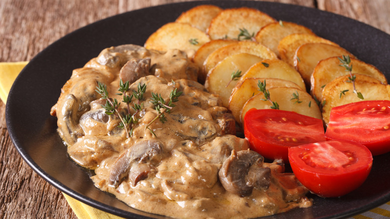 Steak Diane on plate with potatoes and tomatoes