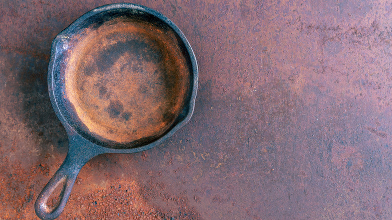 Rusty cast iron pan on brown background