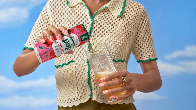 Woman pours Simply Pop strawberry prebiotic soda into glass