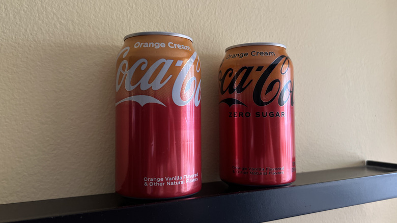 two Coca-Cola Orange Cream cans on a shelf