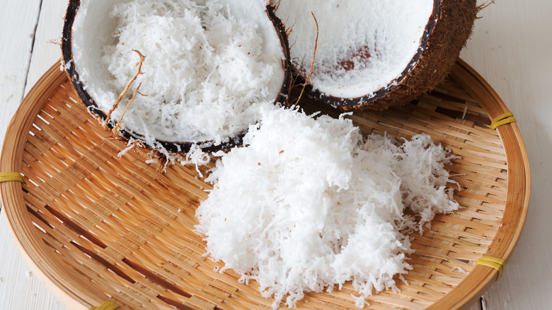 coconut halves beside pile of thin coconut shreds on top of basket