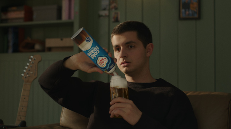 A man is shown swirling Coffee Mate cold foam onto a drink