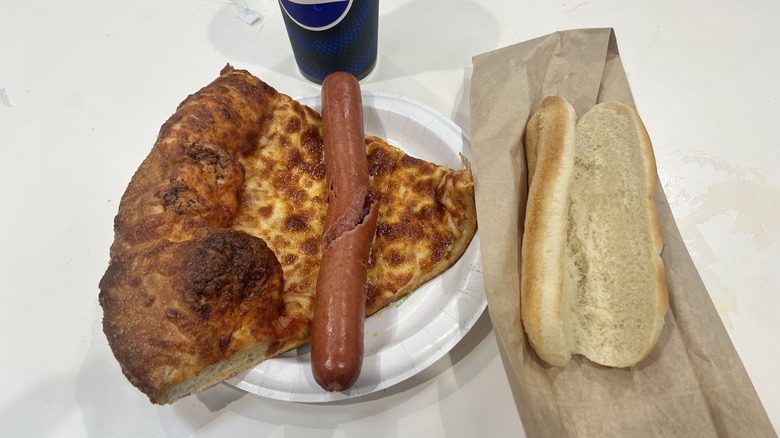 Costco hot dog laying on top of cheese pizza slice