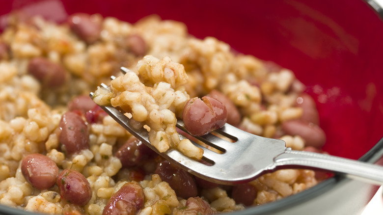 Beans and rice on fork in red bowl