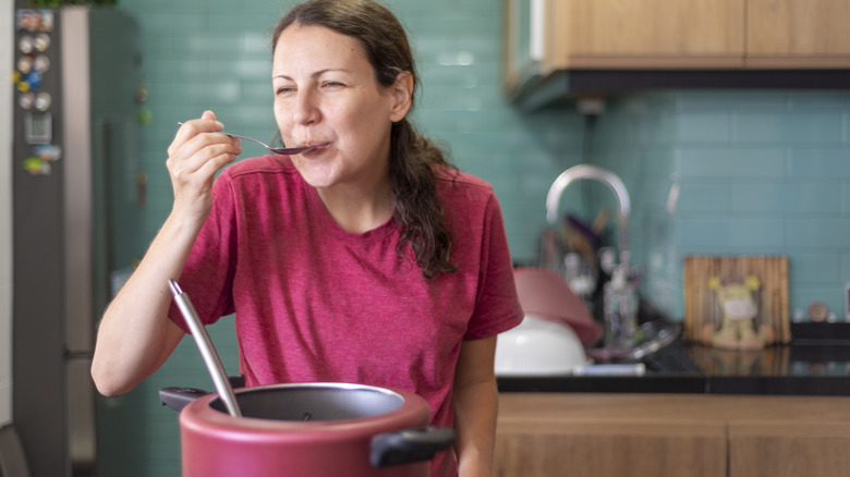 Woman tasting food from pot