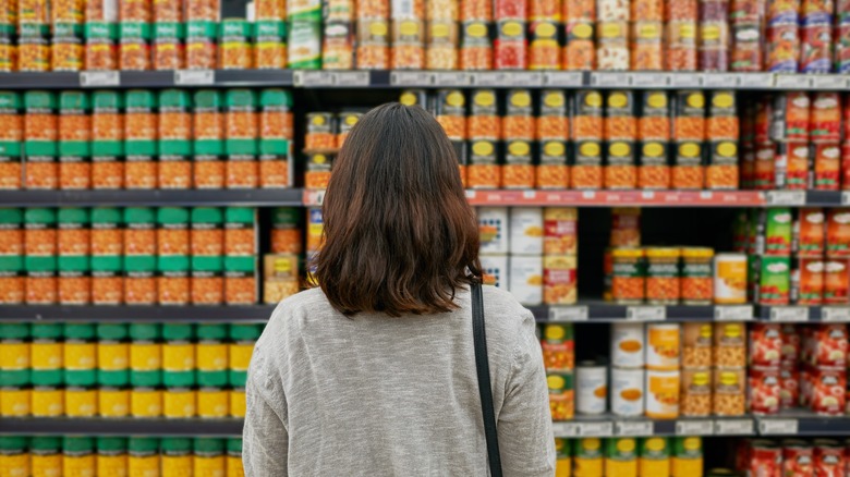 Woman looking at cans in grocery store