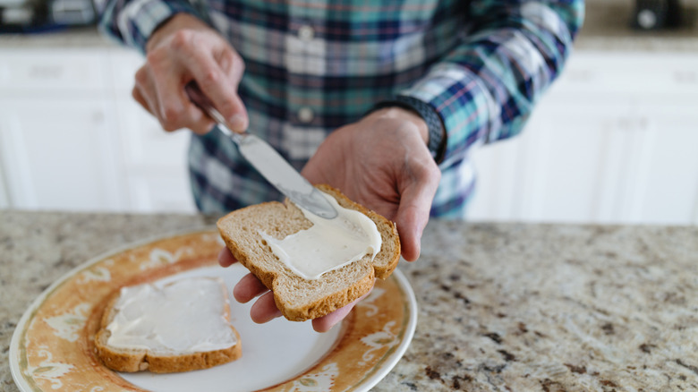 Person spreading mayonnaise on bread