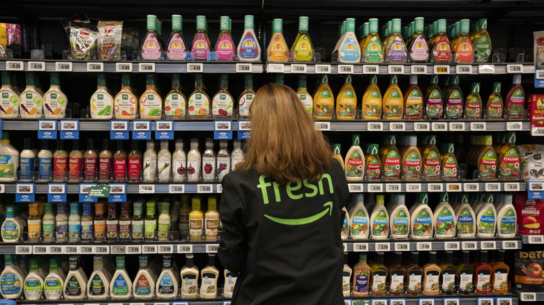 Grocery store employee looking at condiments on shelves