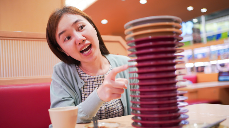 Person counts plates in sushi restaurant