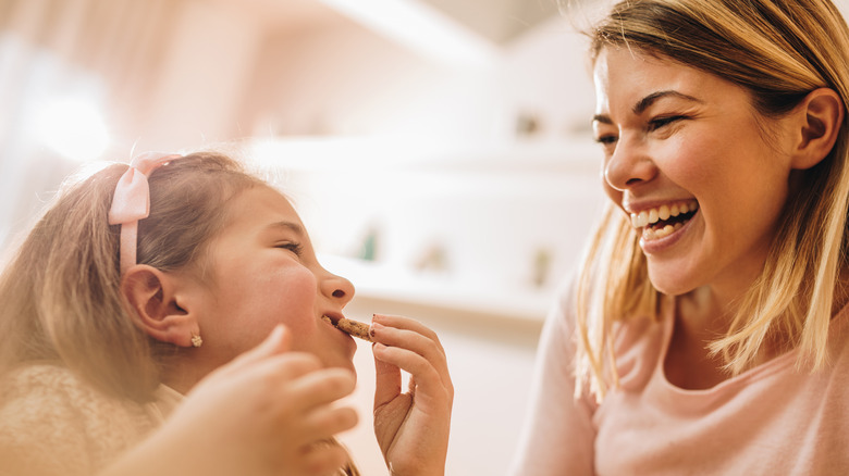 happy little girl eating chocolate chip cookie with mom