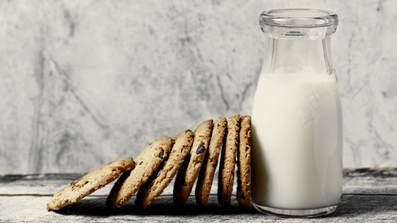 A glass of milk with cookies sitting beside it