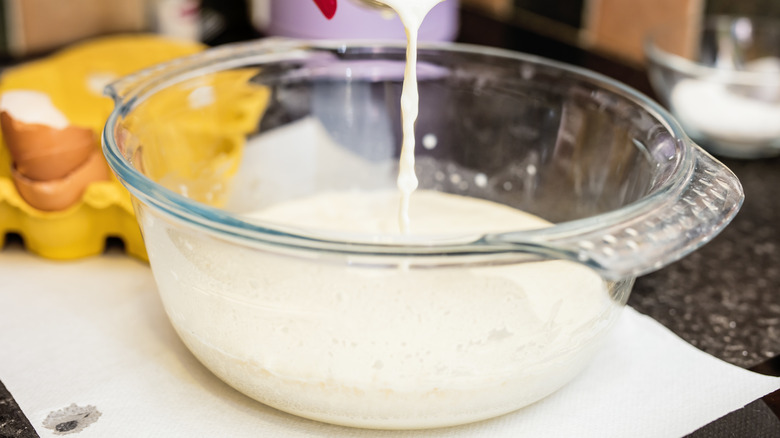 A person pouring milk into a bowl on the kitchen counter