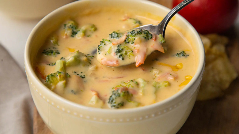 broccoli cheese soup in a white bowl with a metal spoon