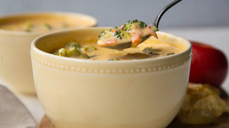 broccoli cheese soup in a white bowl with a metal spoon