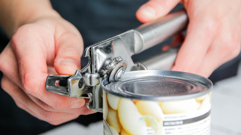 Person opening a can of beans with can opener