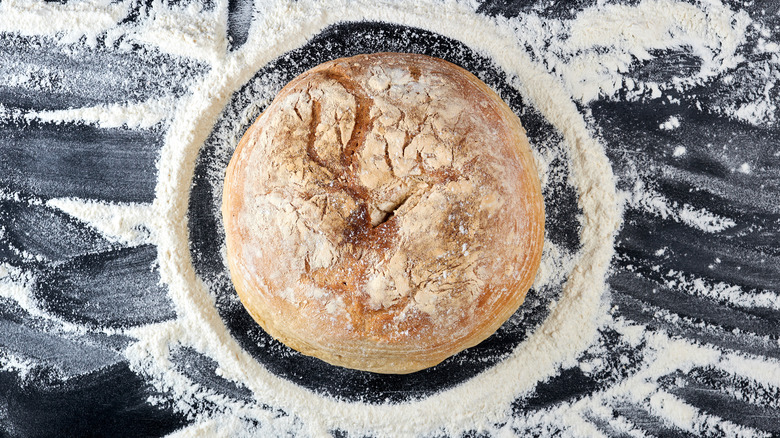 Fresh loaf of bread surrounded by flour