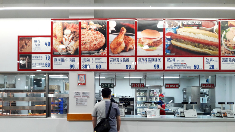 Taiwanese Costco menu mounted on the wall, one man waiting in line to order.