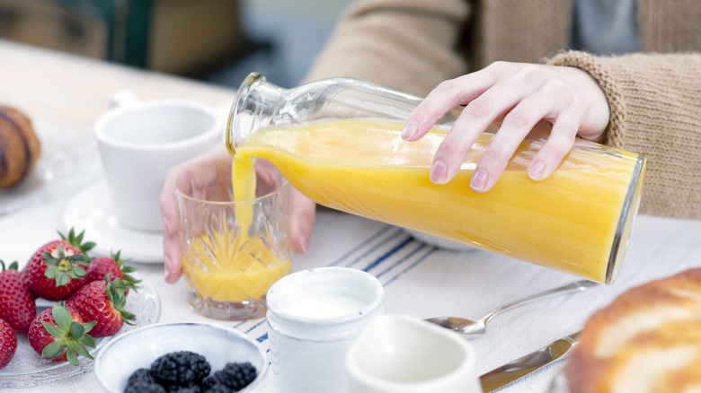 hand pouring orange juice