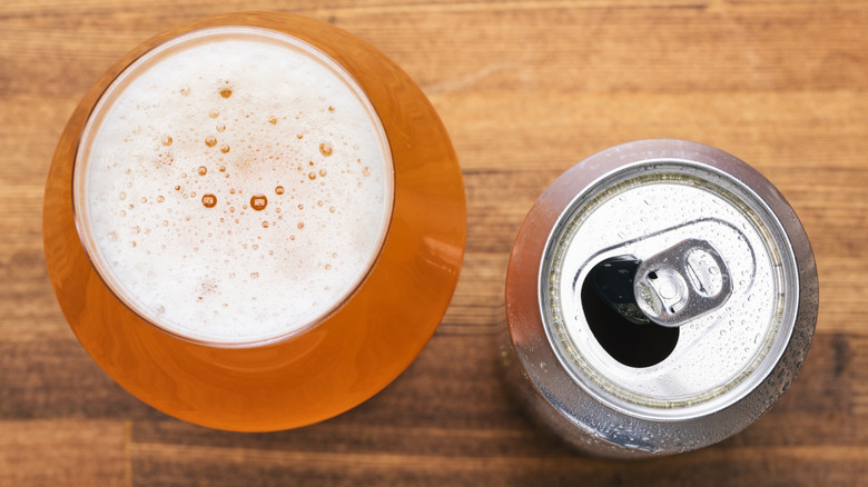 Open can and glass of beer on a wooden surface