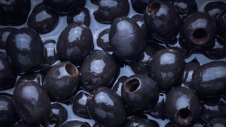 A pile of black olives in brine