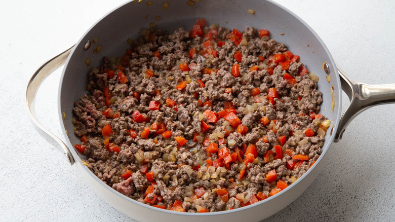 ground beef cooking with onion and bell pepper in skillet