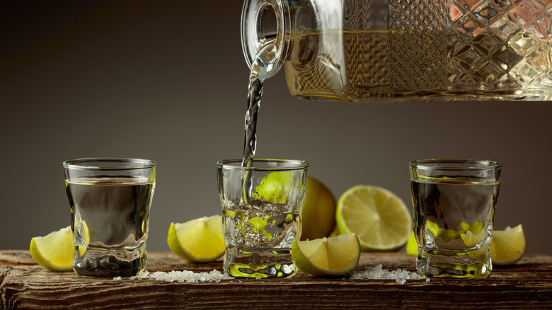 Pouring tequila into shot glasses with lime and salt