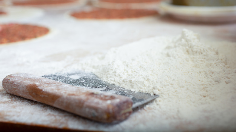 A bench scraper on a pile of flour